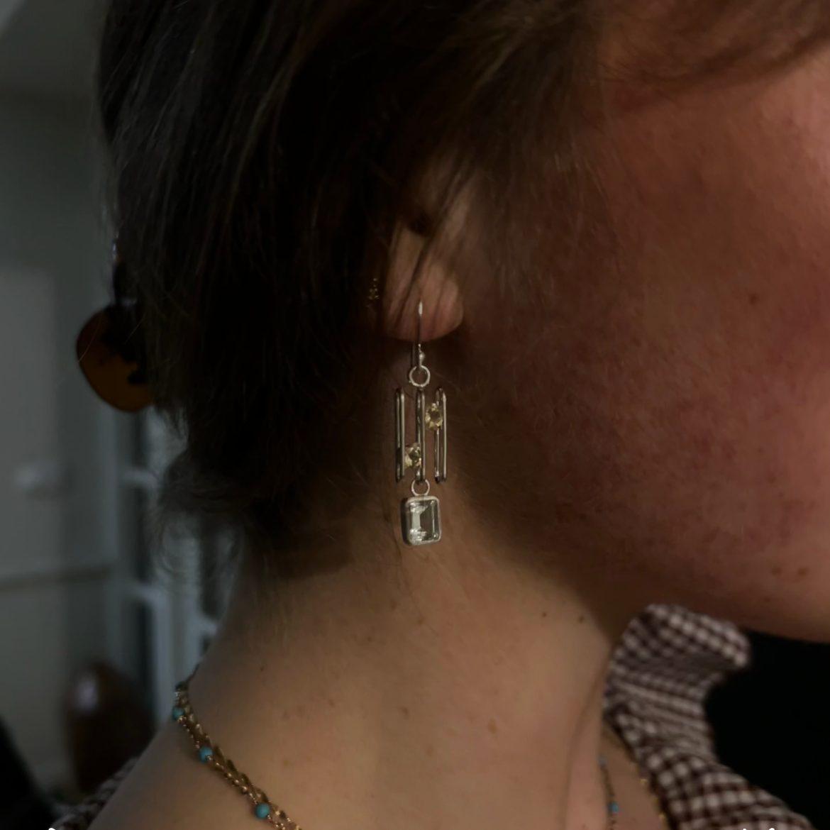Close-up of a person wearing gold earrings with a blurred background