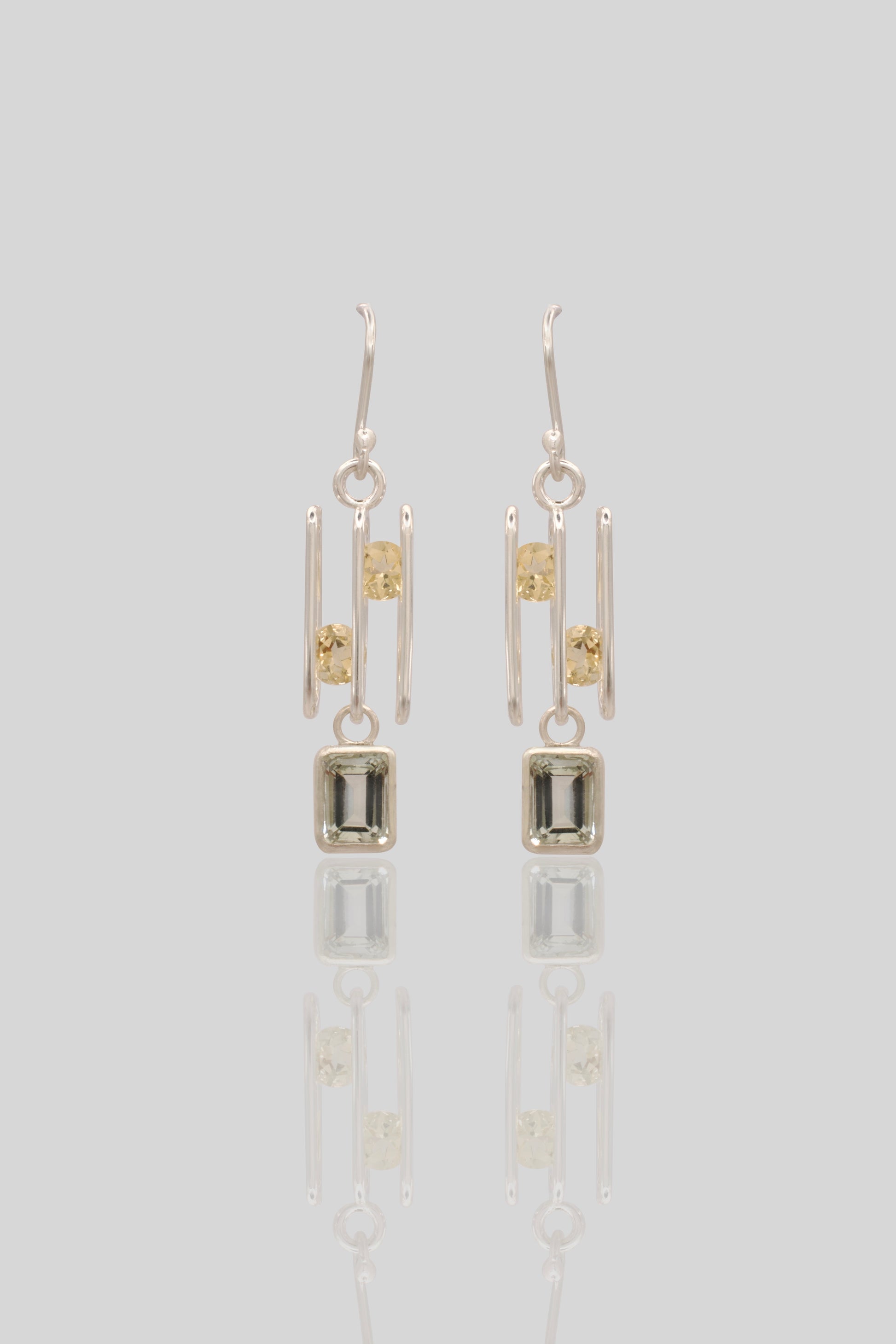 Pair of silver earrings with rectangular gemstones on a light gray background