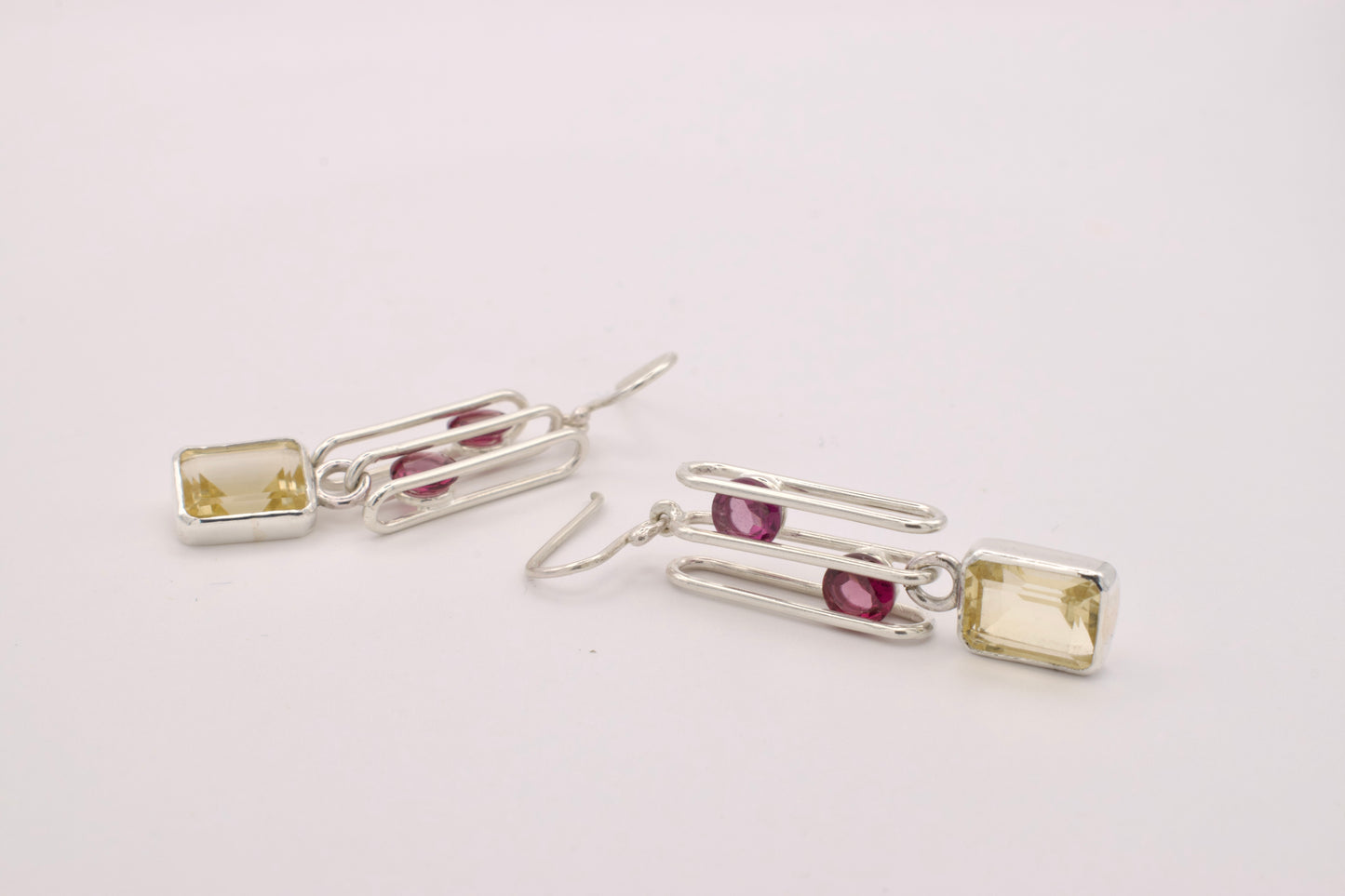 Pair of silver earrings with gemstones on a light gray background
