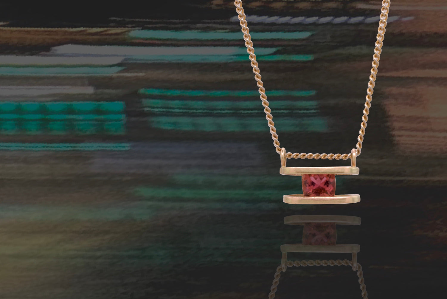 Necklace with a pink pendant on a reflective surface