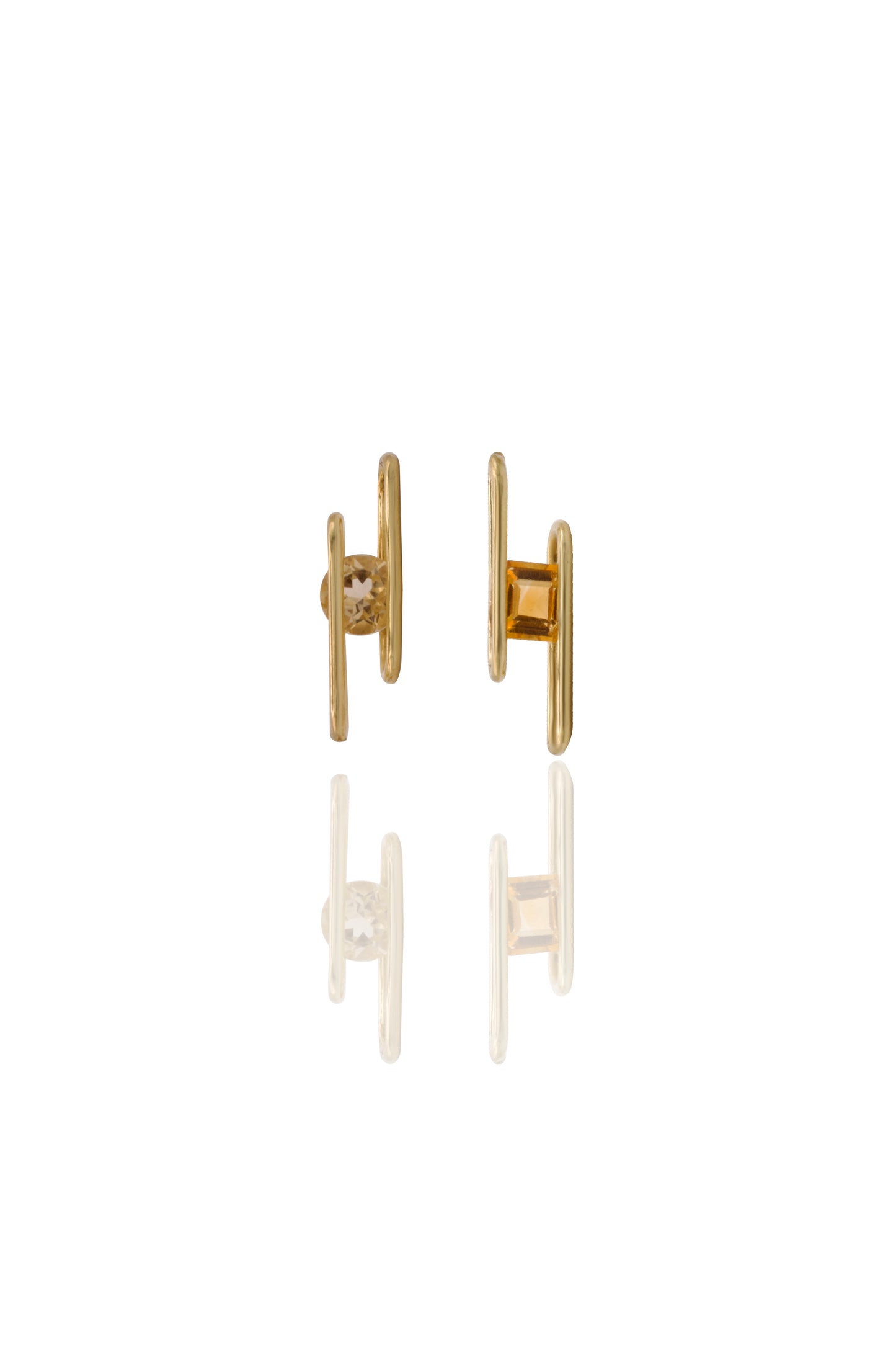 Gold earrings with an orange gemstone on a white background