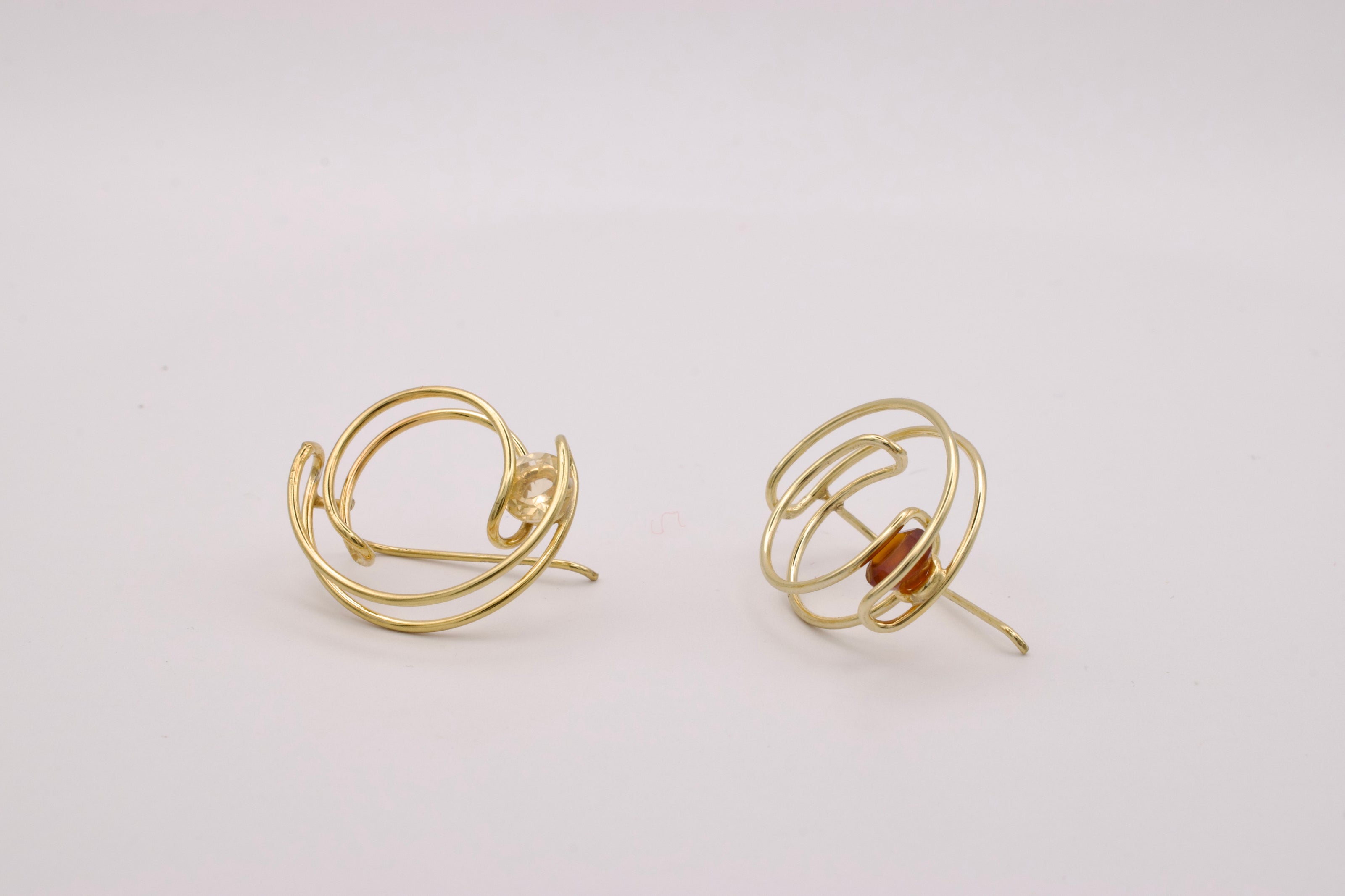 Gold wire earrings on a light gray background