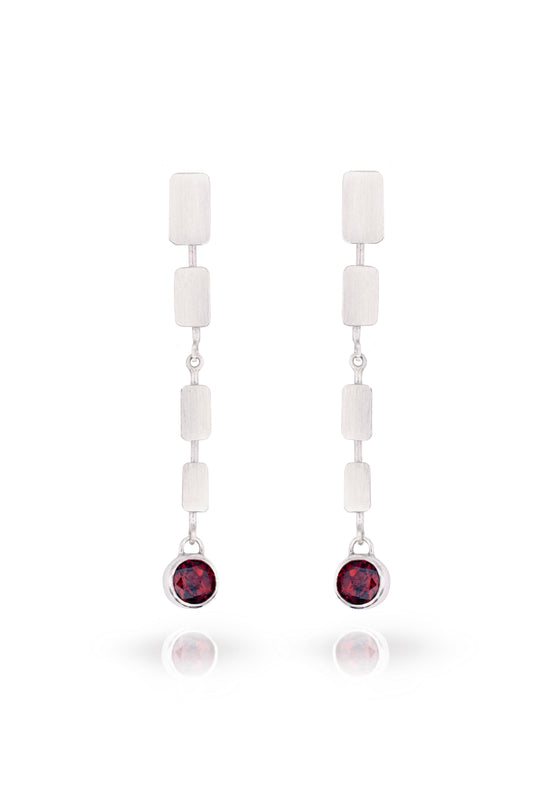 Pair of earrings with white beads and red gemstones on a white background