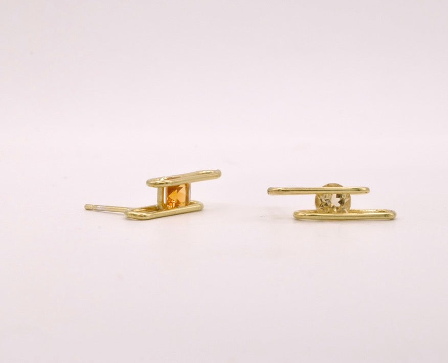 Pair of gold bar earrings on a light pink background