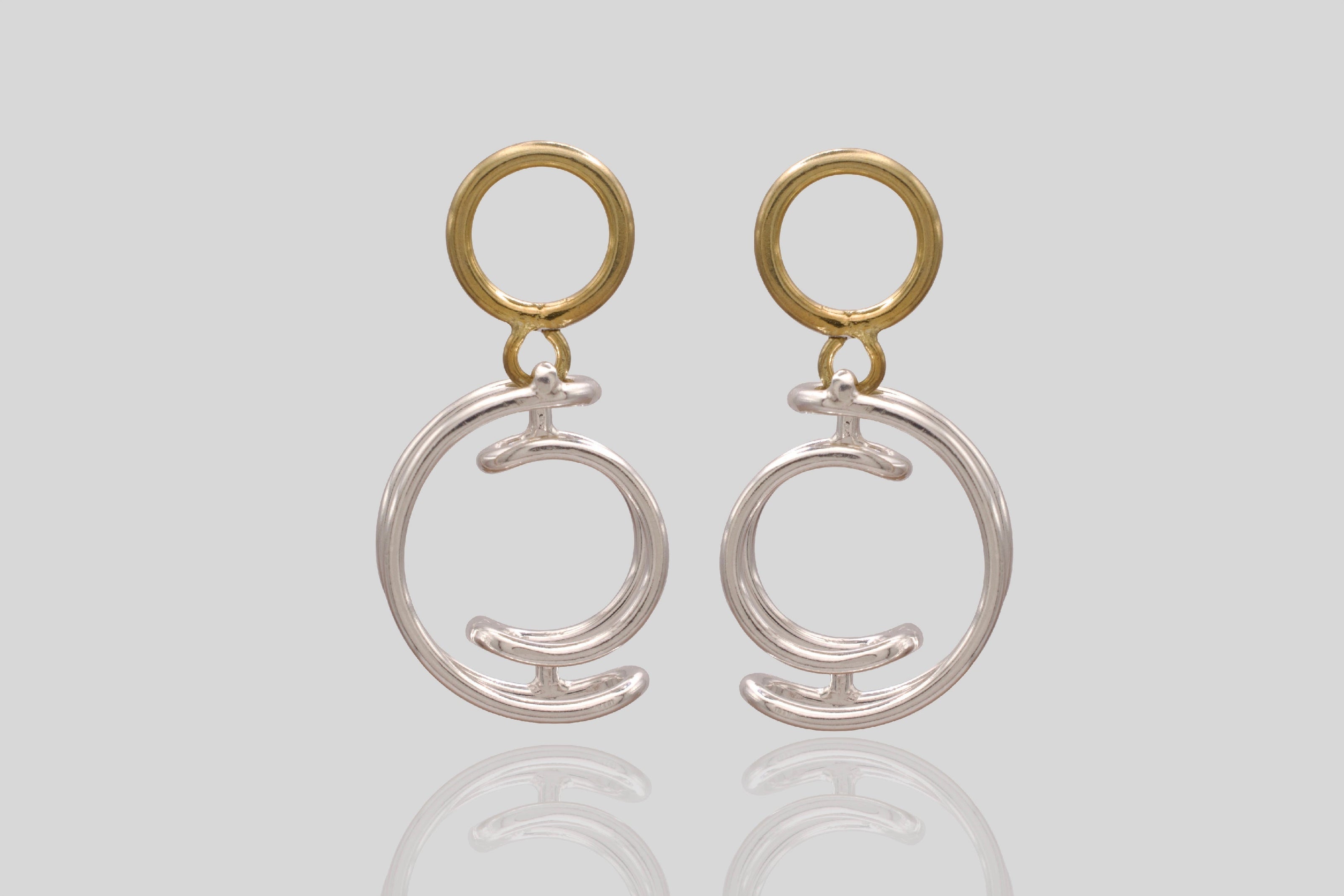 Pair of gold and silver earrings on a light grey background