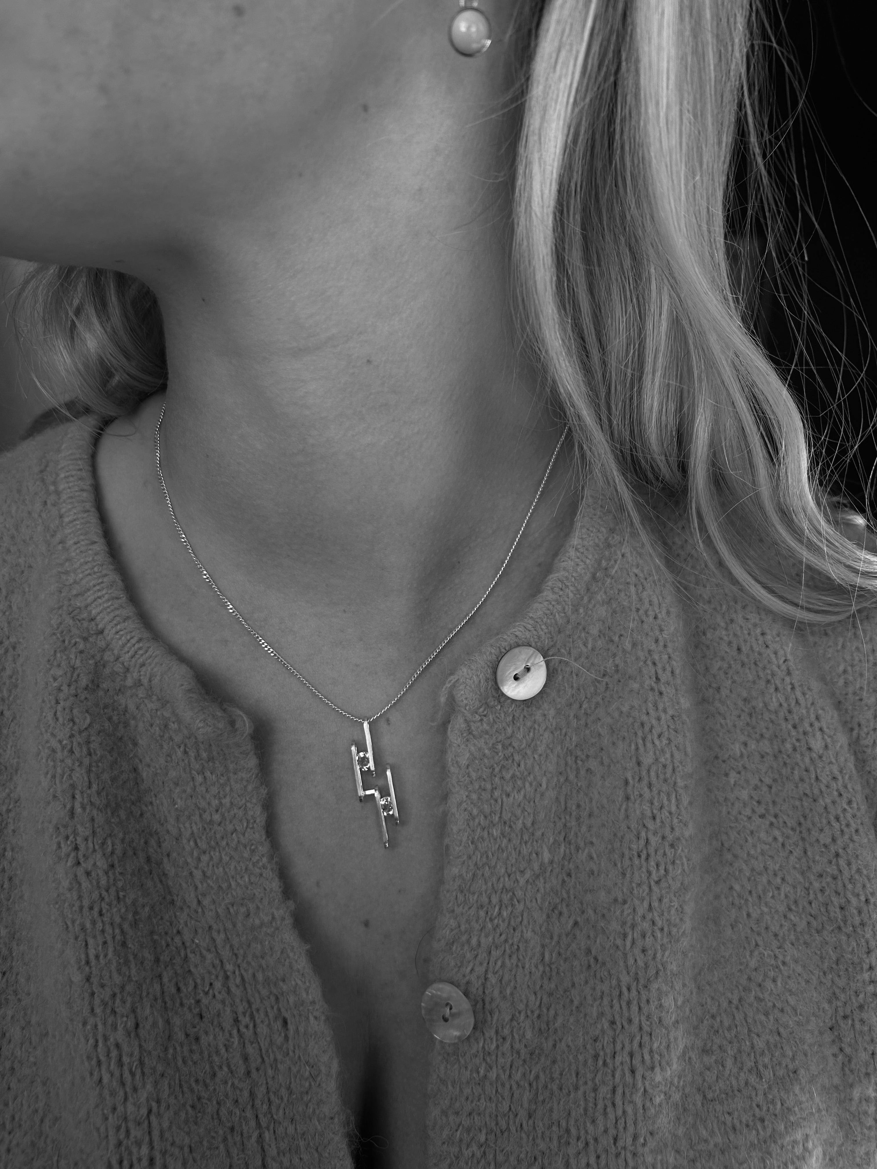 silver necklace with wire pendant being worn