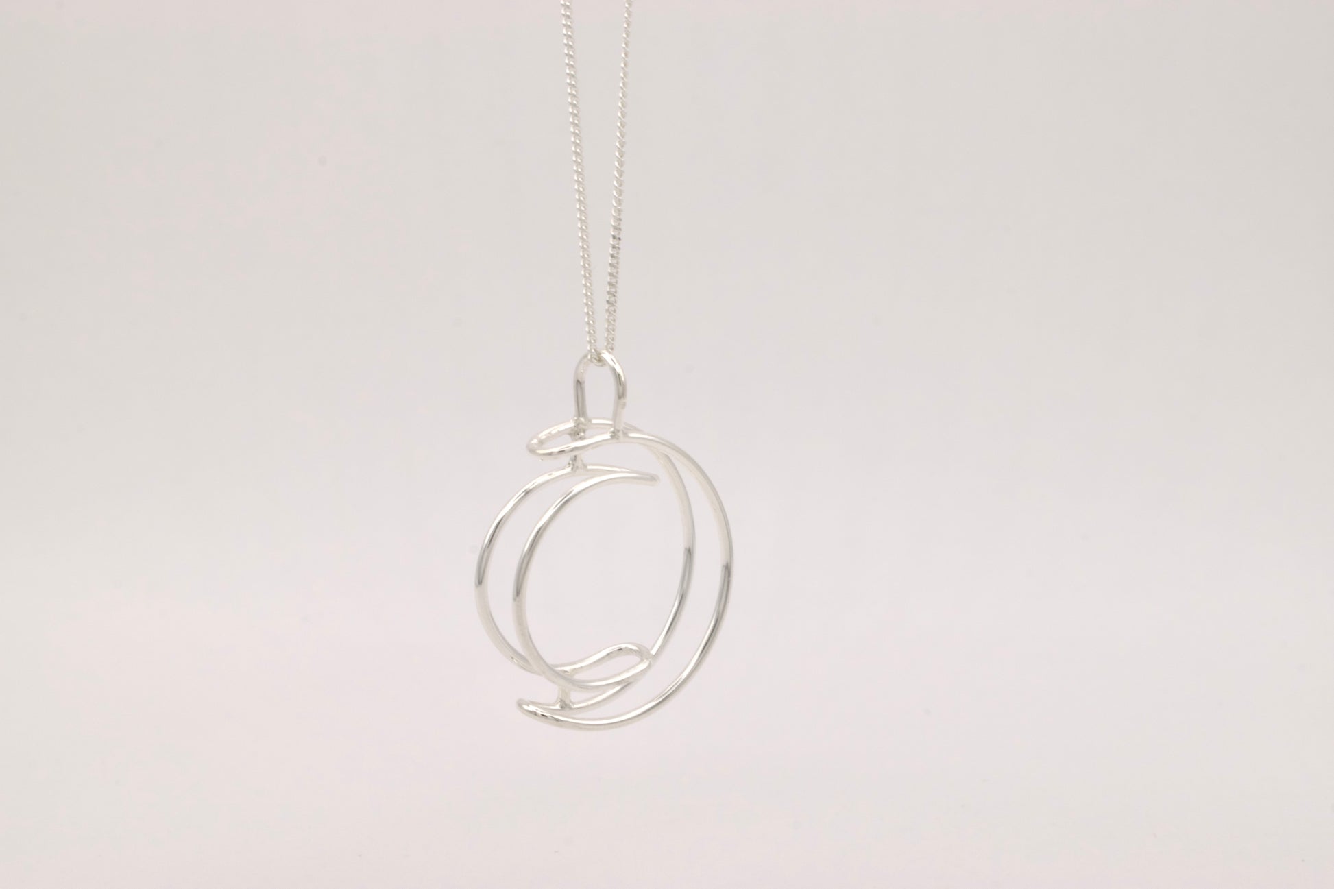 Silver necklace with a unique pendant on a light gray background