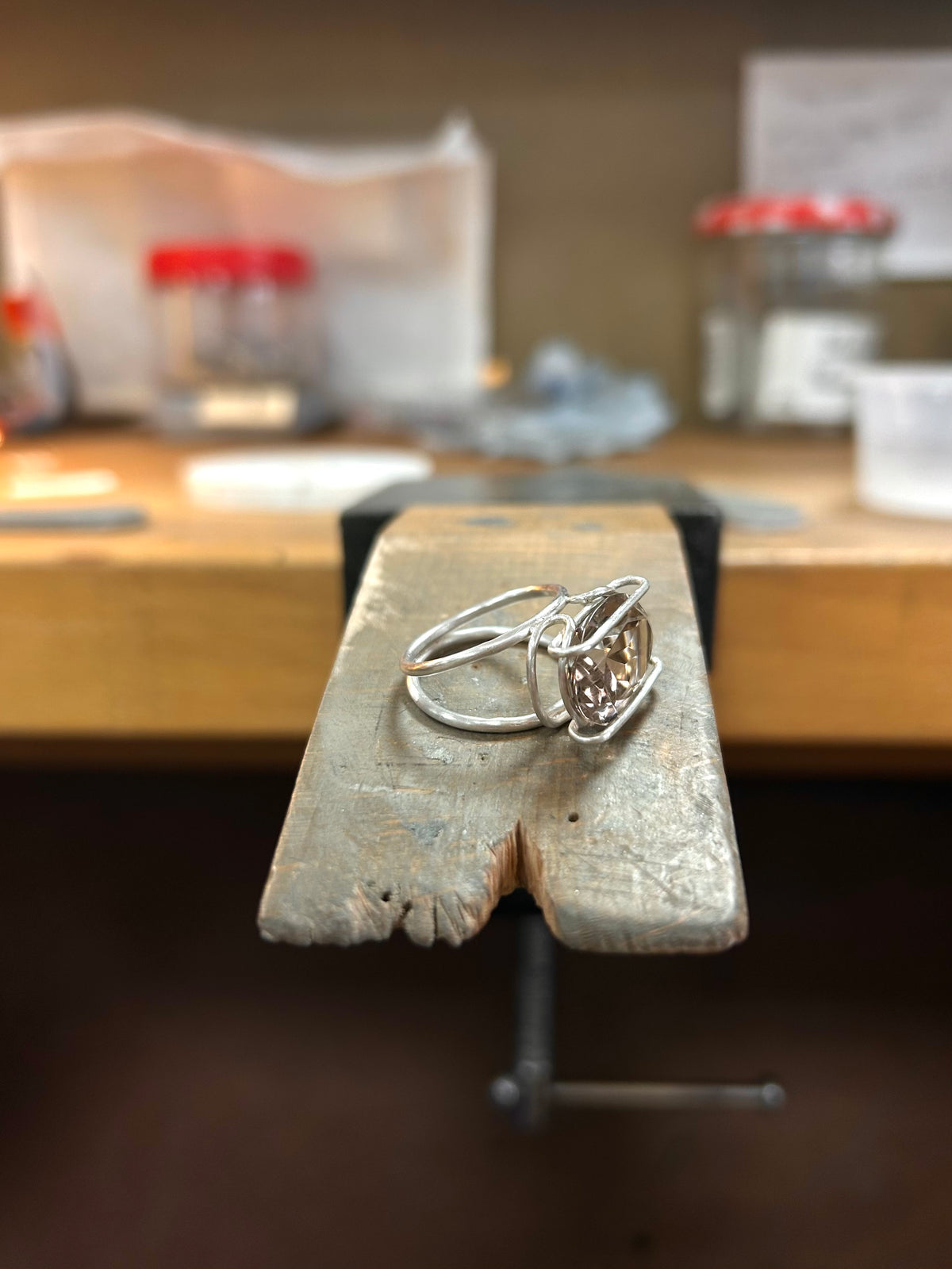 Silver ring with brown stone on a wooden block with a blurred background